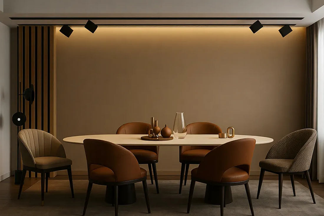 Elegant dining area featuring an oval table, leather chairs, and a modern black magnetic track lighting system with directional spot fixtures, illuminating a neutral accent wall.